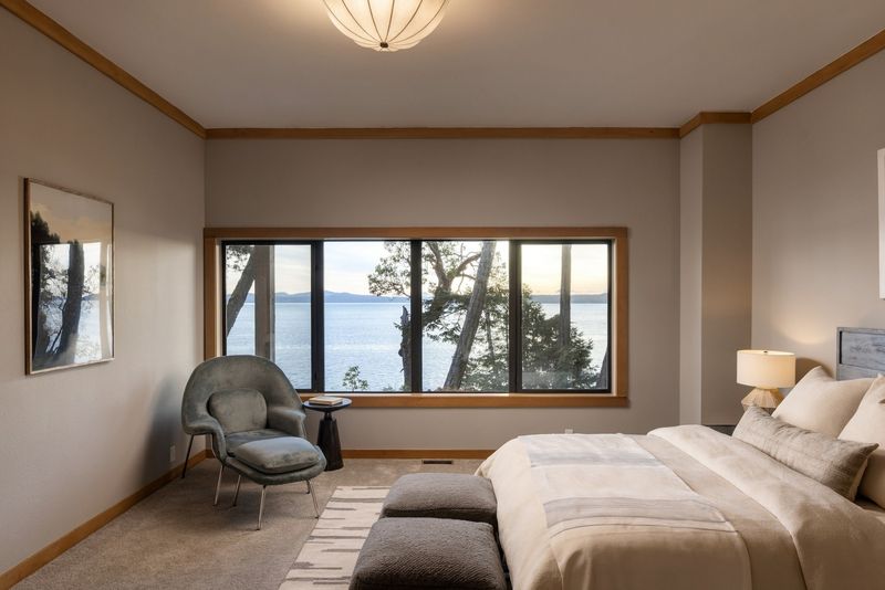 Bedroom at BrightWoods with a wall of windows overlooking the water
