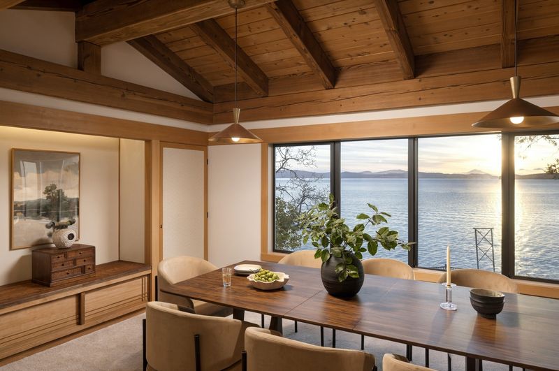 Dining room at BrightWoods with a wall of windows over the water and a beam ceiling