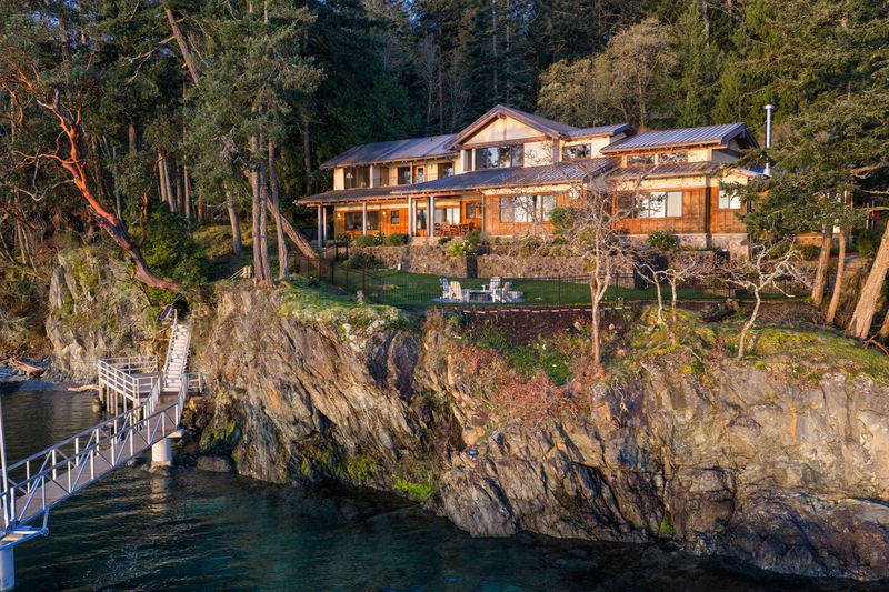 Timber-frame residence above the rock shoreline at BrightWoods, with the dock below