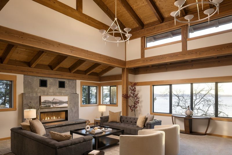 Living room at BrightWoods with beam vaulted ceiling, fireplace and windows toward the water